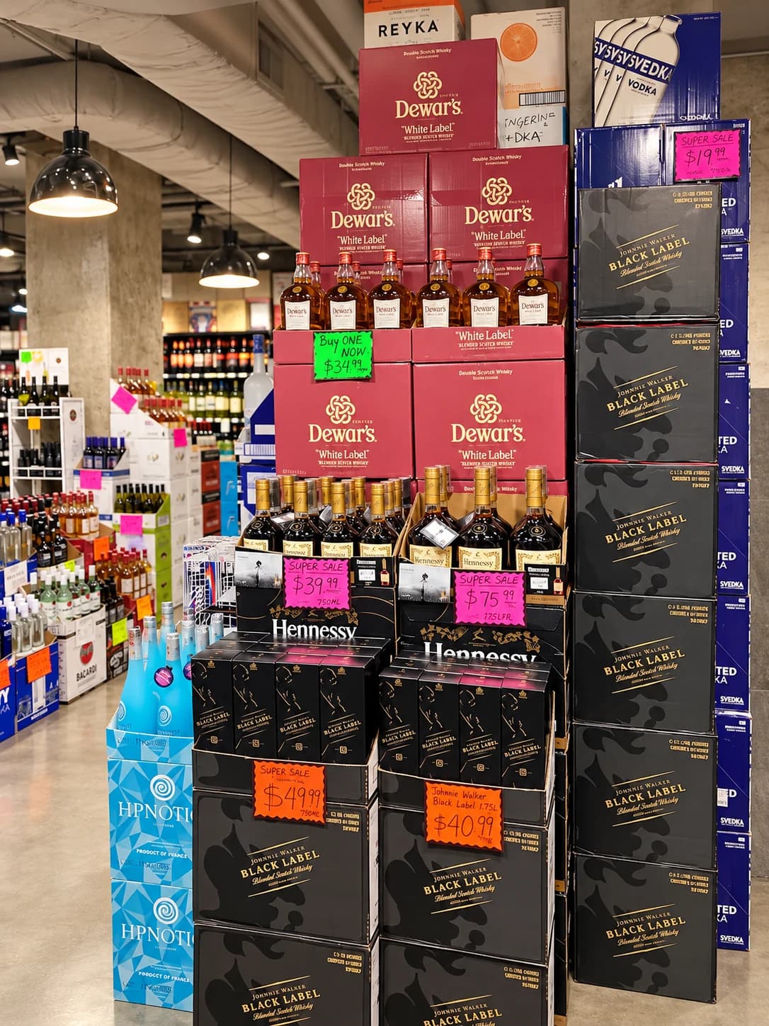 Tall displays of Dewar’s, Johnnie Walker and Hennessy cases, with colorful in-store sale cards.