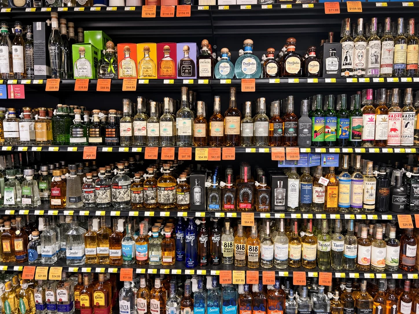 Tequila and mezcal shelves with blanco, reposado and añejo bottles and gift boxes.
